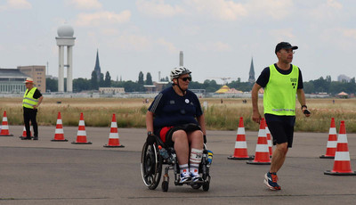 Rollstuhlfahrer und Guide beim Lauf