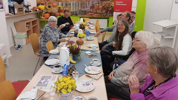 Menschen sitzen bei Kaffee und Kuchen am Tisch