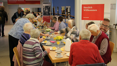 Langer Tisch mit vielen Leuten bei Kaffee und Kuchen