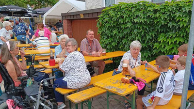 Menschen sitzen im Freien auf Bänken