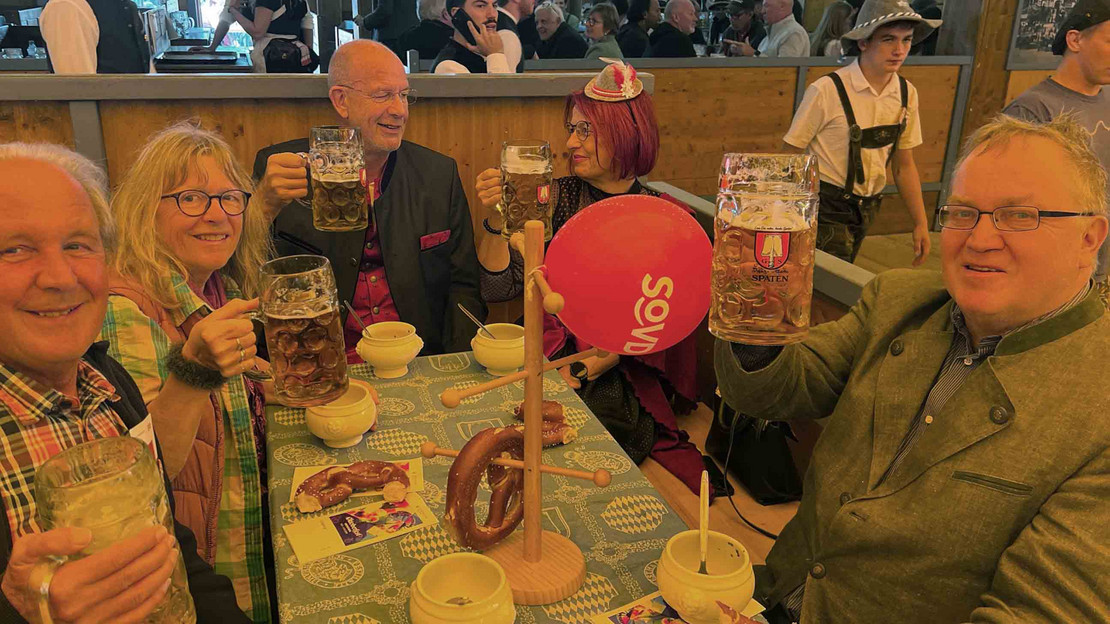 Männer und Frauen sitzen am Tisch mit Bierkrügen
