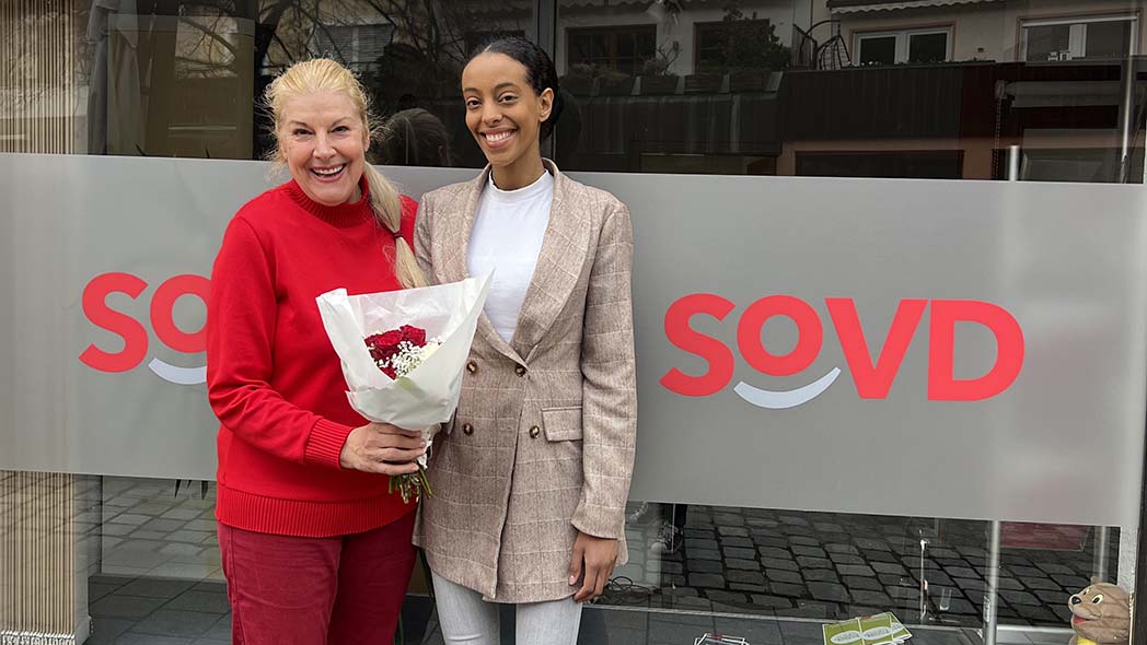 Zwei Frauen, eine hält einen Blumenstrauß