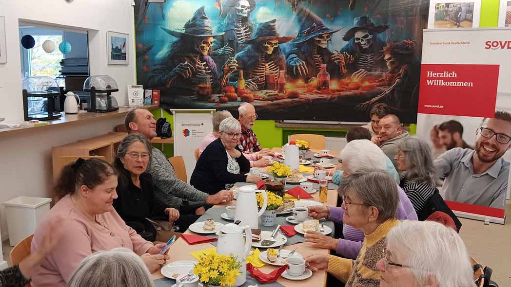 Frauen und Männer sitzen am Tisch, im Hintergrund eine Horrorplakat