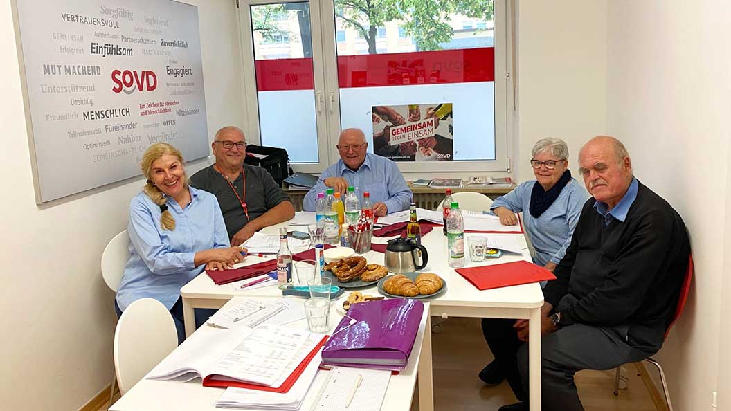 Fünf Personen sitzen an einem Tisch. 